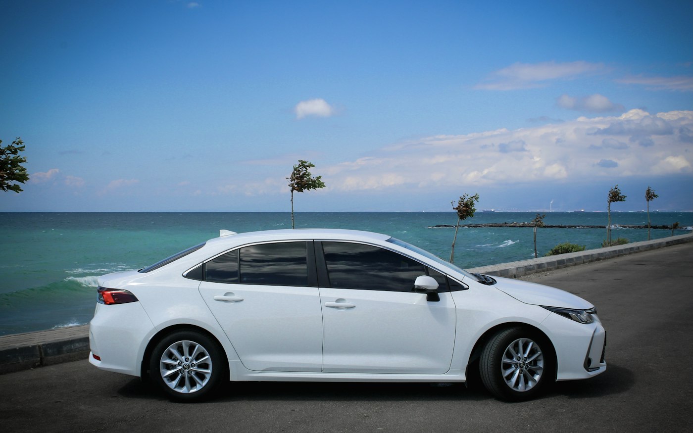 Biała Toyota Corolla sedan przy nadmorskiej drodze